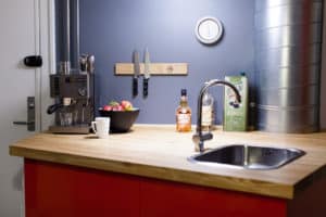 Køkken med espressomaskine, frugt, knivskinne og køkkenbord.