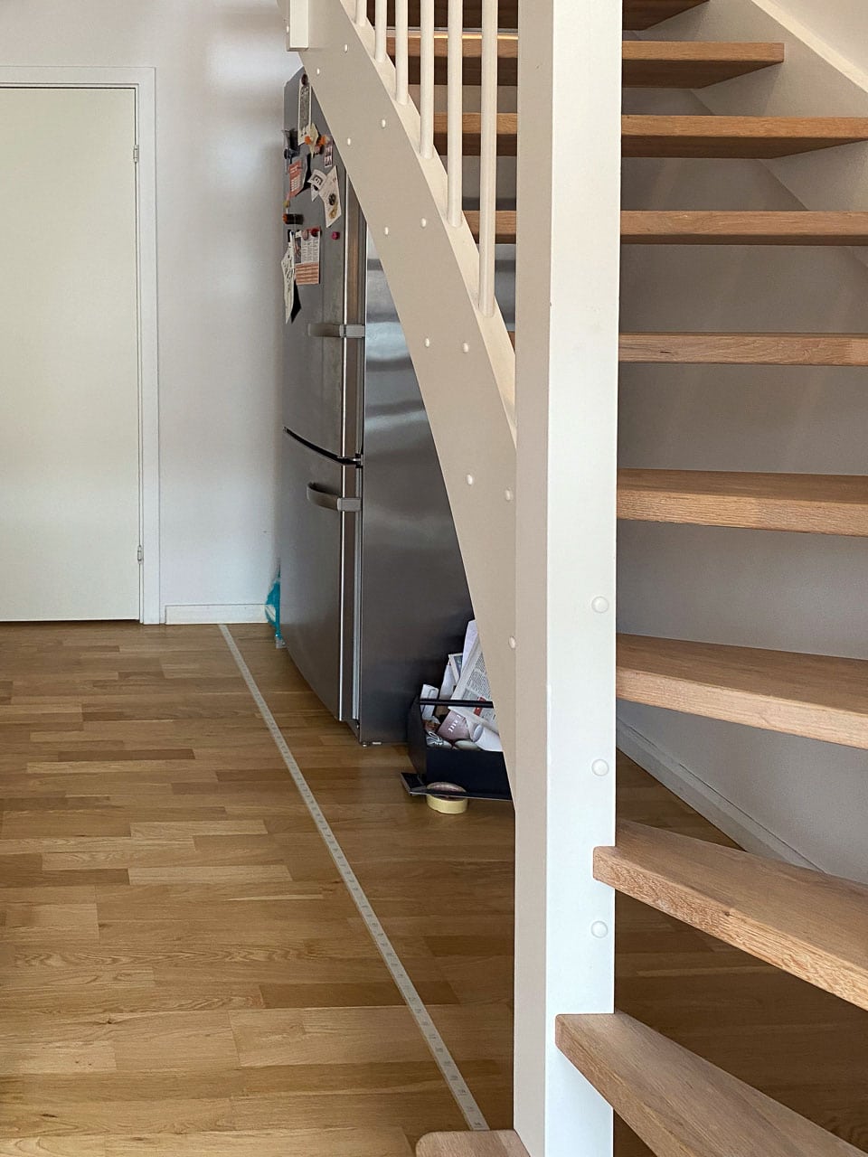 Før-billede: fritstående køleskab under åben, ulukket trappe – pladsen virker rodet og uudnyttet før den skræddersyede løsning