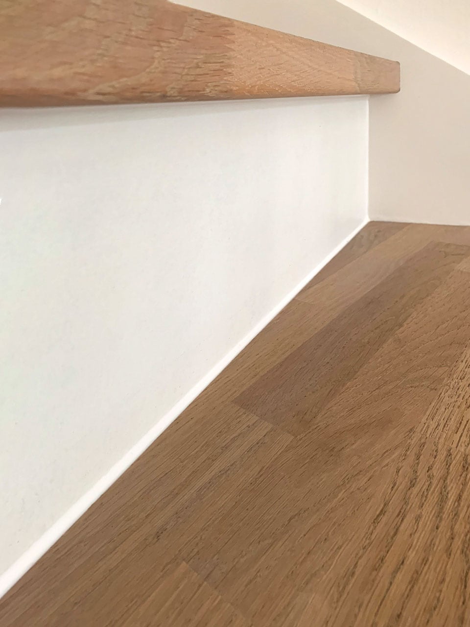 Lukket egetræstrin med flot, ensartet fuge mod hvid trappevange – detalje fra opbevaring under trappe i Nordvest, København.