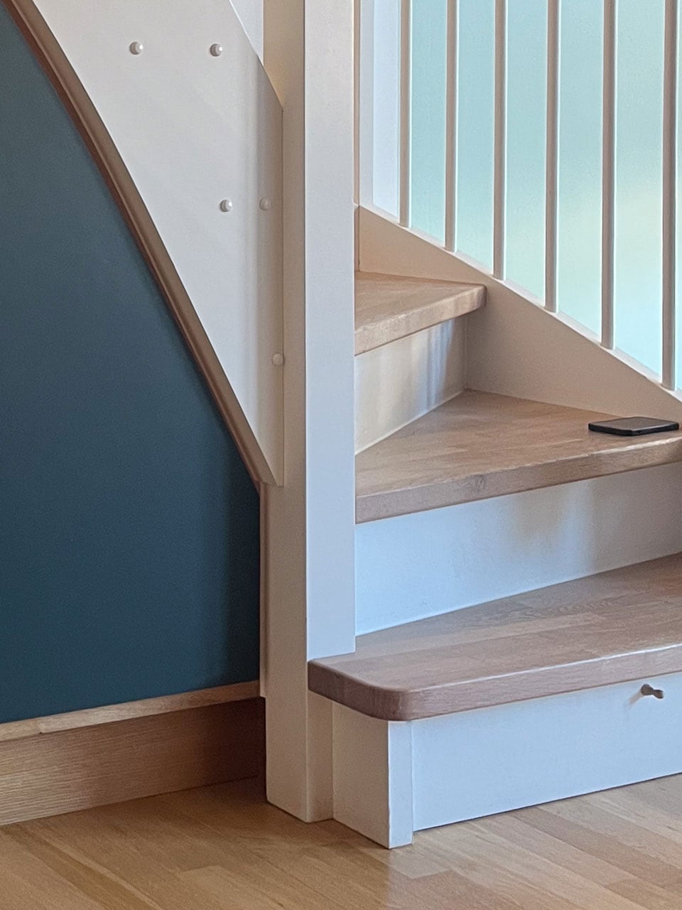 Laveste del af opbevaring under trappe med lukket grøn linoleumslåge og diskret udtræksskuffe på hjul under nederste egetræstrin