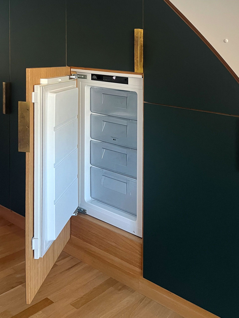 Fuldt integreret fryser under trappe – grøn Forbo linoleumslåge åben, hvor fryserdøren følger med ud