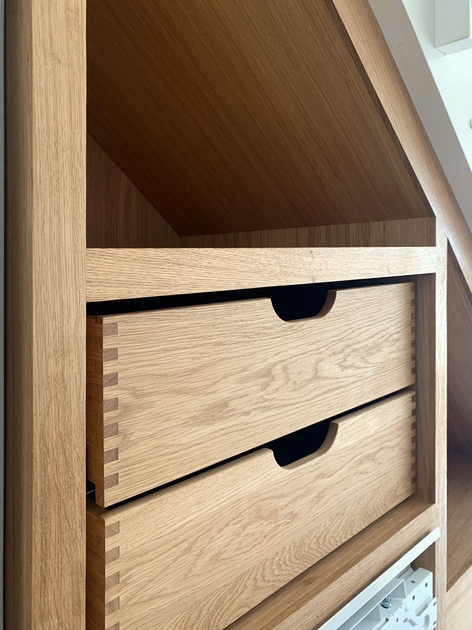 Nærbillede af to mindre fingersamlede massiv-eg-skuffer med elegant buet greb skåret i frontens øverste kant – før montering af låger