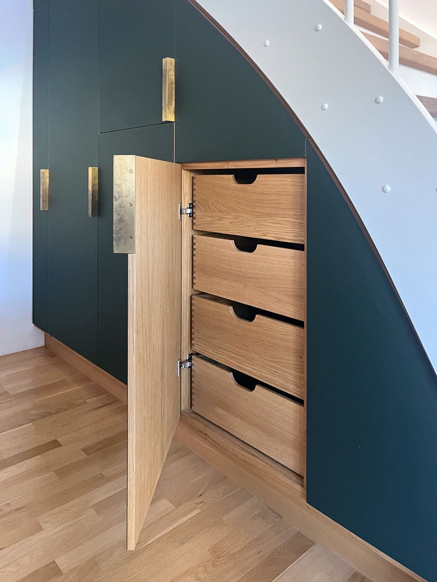 Åben grøn linoleumslåge viser egetræsfiner på indersiden og fire dybe fingersamlede skuffer i massiv egetræ – køkkenopbevaring under trappe